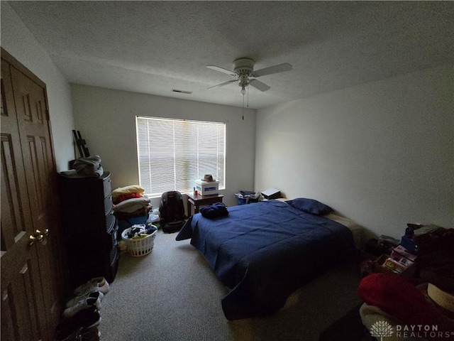 carpeted bedroom featuring ceiling fan and a textured ceiling