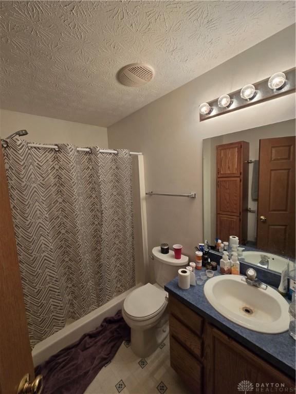 bathroom with a textured ceiling, vanity, toilet, and walk in shower