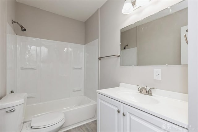 full bathroom featuring washtub / shower combination, hardwood / wood-style floors, vanity, and toilet