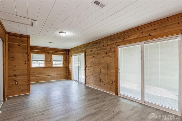 unfurnished room with wood-type flooring and wooden walls