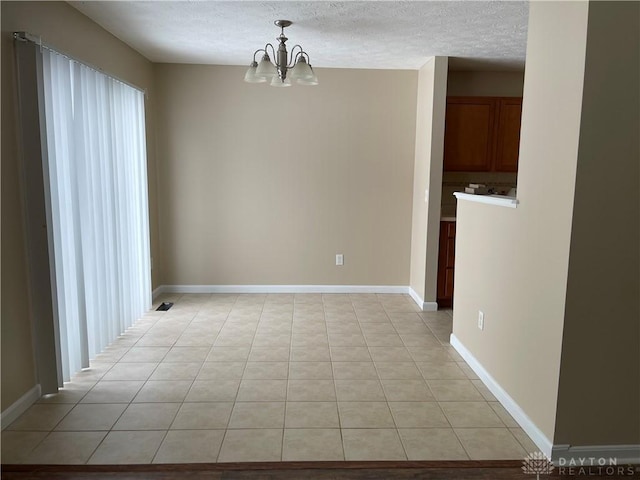 unfurnished dining area featuring light tile patterned floors, a textured ceiling, and an inviting chandelier