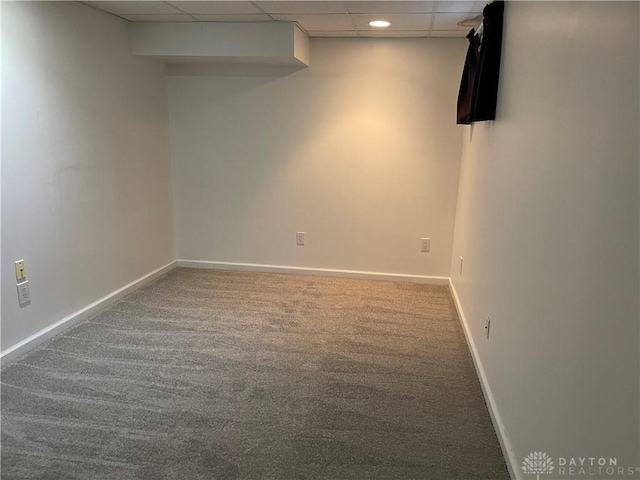 carpeted empty room featuring a drop ceiling