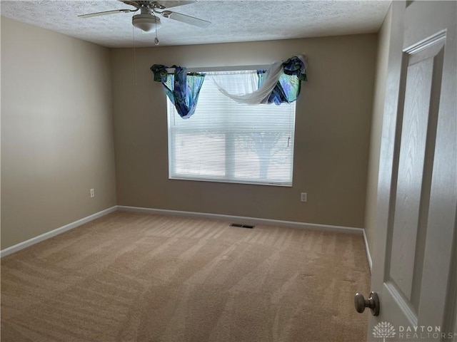 carpeted empty room with ceiling fan and a textured ceiling