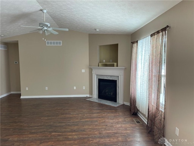 unfurnished living room featuring ceiling fan, dark hardwood / wood-style floors, vaulted ceiling, a textured ceiling, and a fireplace