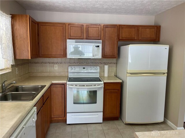 kitchen featuring sink, backsplash, a textured ceiling, white appliances, and light tile patterned flooring