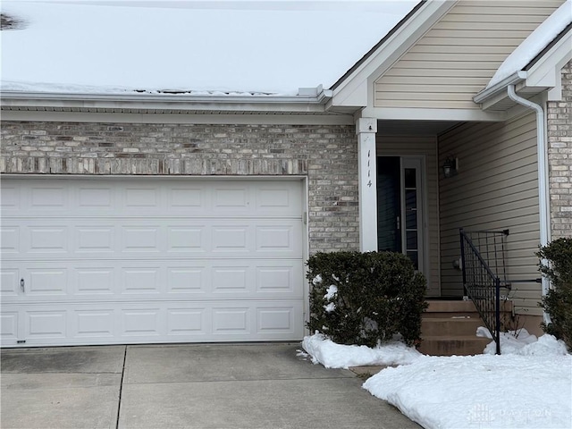 snow covered property entrance featuring a garage