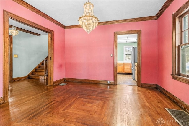 spare room featuring a notable chandelier, parquet flooring, and crown molding