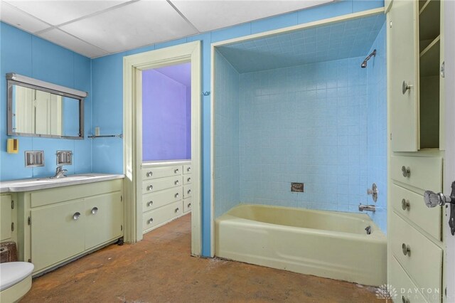 full bathroom with tiled shower / bath combo, concrete floors, toilet, a paneled ceiling, and vanity