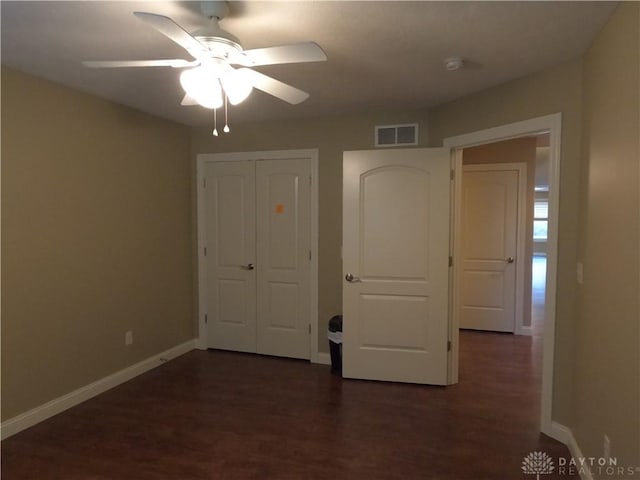 unfurnished bedroom featuring ceiling fan, dark hardwood / wood-style flooring, and a closet