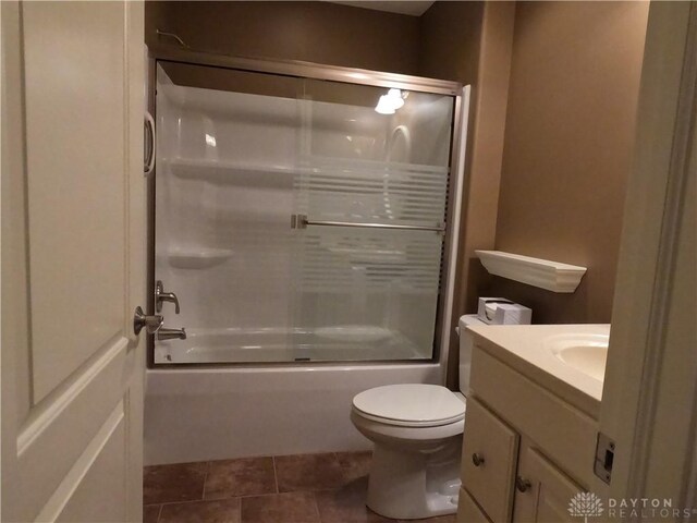 full bathroom featuring tile patterned floors, vanity, bath / shower combo with glass door, and toilet