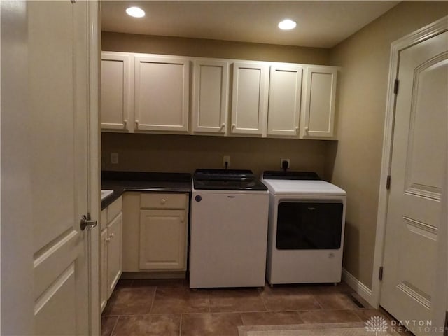 laundry room featuring cabinets, separate washer and dryer, and dark tile patterned flooring