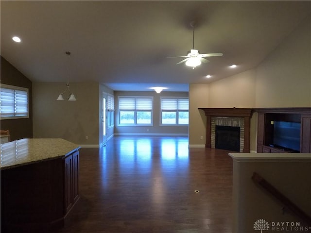 living room featuring dark hardwood / wood-style flooring, a brick fireplace, ceiling fan, and vaulted ceiling