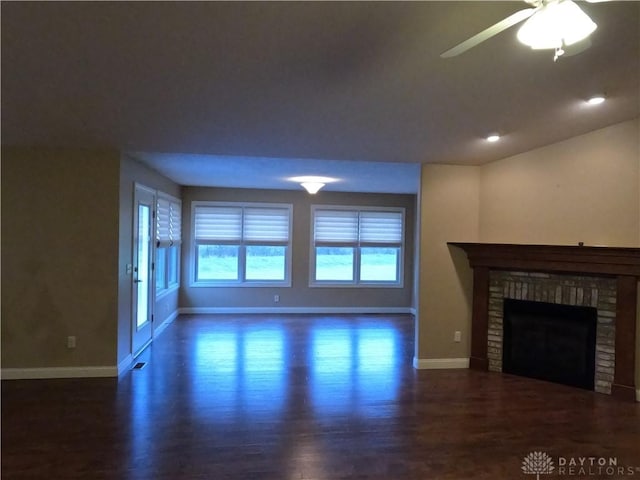 unfurnished living room featuring ceiling fan, dark hardwood / wood-style floors, and a fireplace