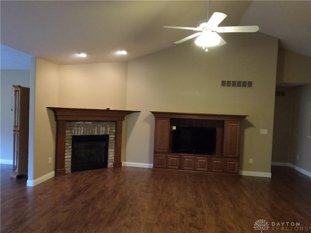 unfurnished living room with a brick fireplace, vaulted ceiling, ceiling fan, and dark wood-type flooring