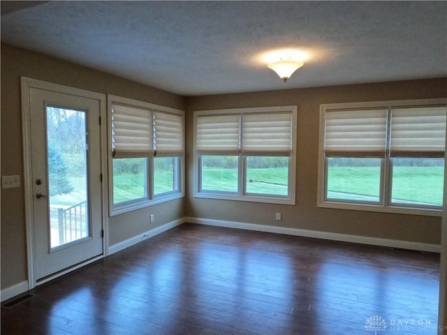 unfurnished room featuring plenty of natural light and dark wood-type flooring