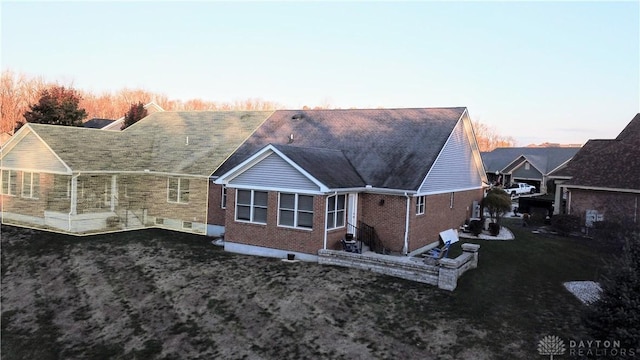 back house at dusk featuring a lawn