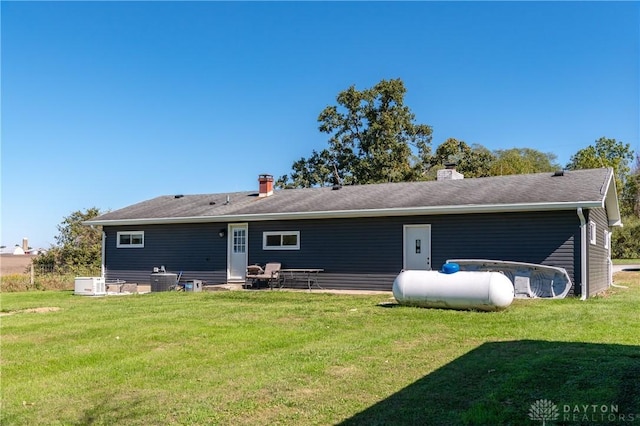 back of house featuring a lawn and a chimney