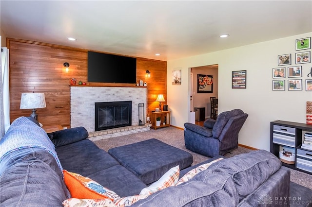 living room featuring baseboards, carpet, wood walls, recessed lighting, and a fireplace