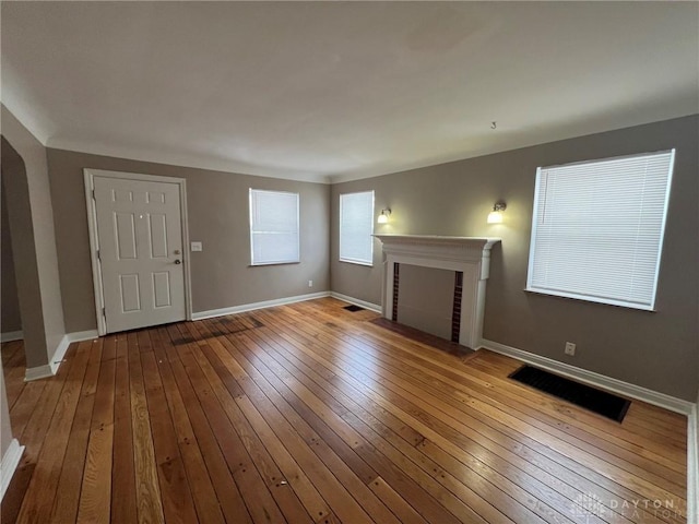 unfurnished living room with light hardwood / wood-style floors and a brick fireplace