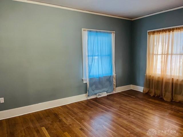 empty room featuring dark hardwood / wood-style flooring and crown molding