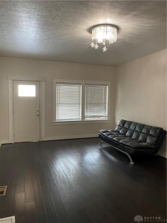 foyer with a notable chandelier, dark hardwood / wood-style floors, and a textured ceiling