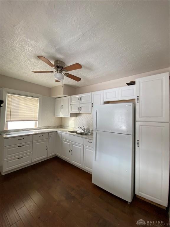 kitchen featuring white fridge, white cabinetry, dark hardwood / wood-style floors, and sink