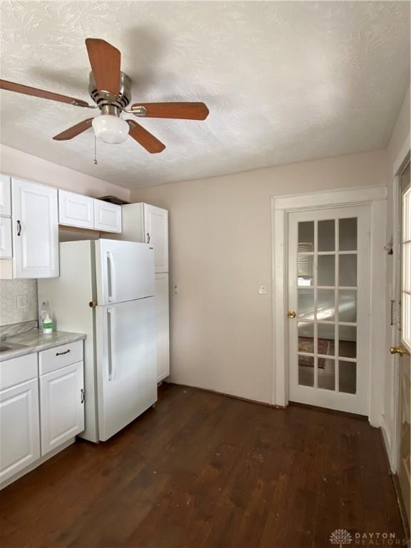 kitchen featuring white cabinets, ceiling fan, white fridge, and dark wood-type flooring