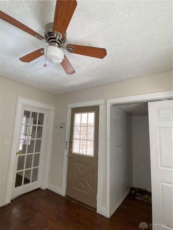 foyer entrance featuring ceiling fan, dark wood-type flooring, and a textured ceiling