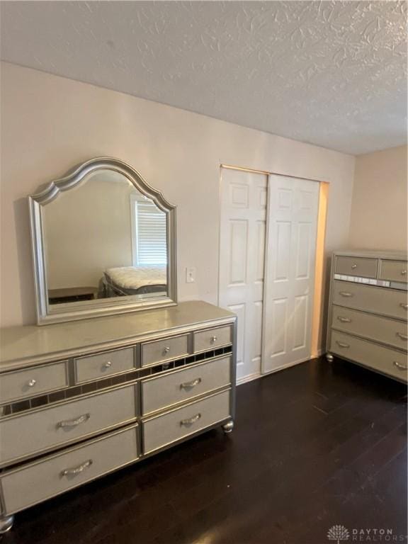 bedroom with a textured ceiling, a closet, and dark hardwood / wood-style floors