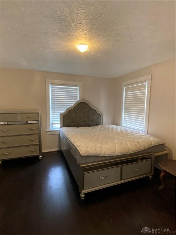 unfurnished bedroom featuring a textured ceiling and dark hardwood / wood-style floors