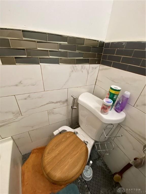 bathroom with toilet and tile walls