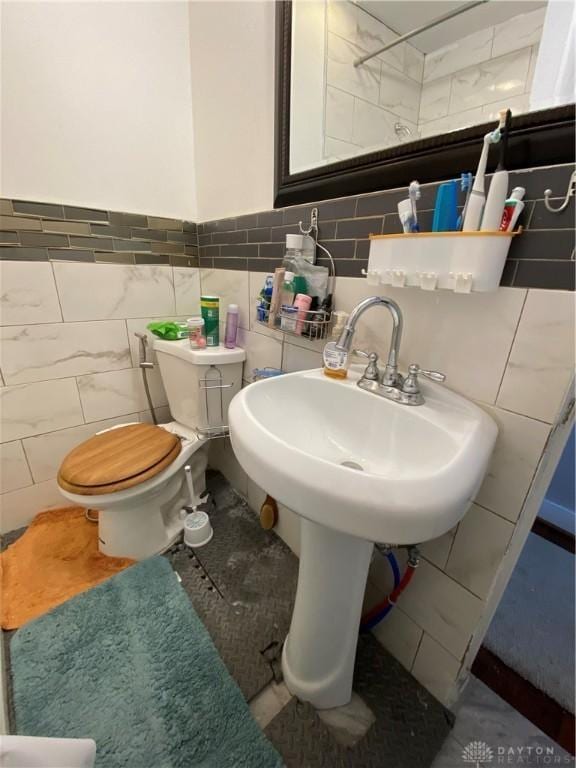 bathroom featuring toilet and tile walls