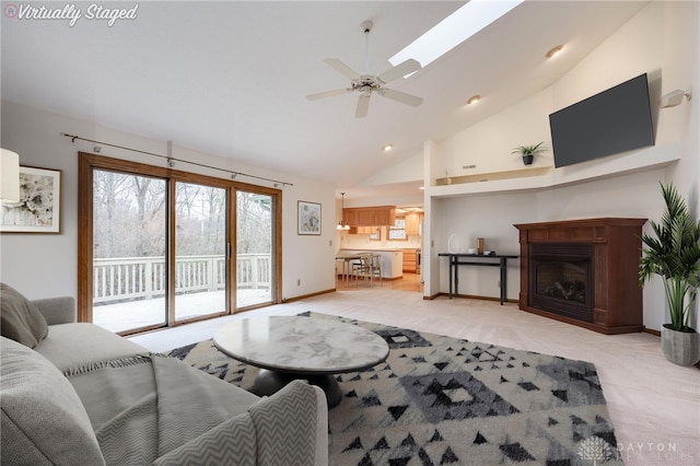 living room featuring ceiling fan, high vaulted ceiling, and a skylight