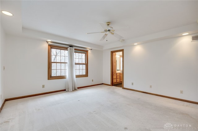 spare room featuring light colored carpet, a tray ceiling, and ceiling fan