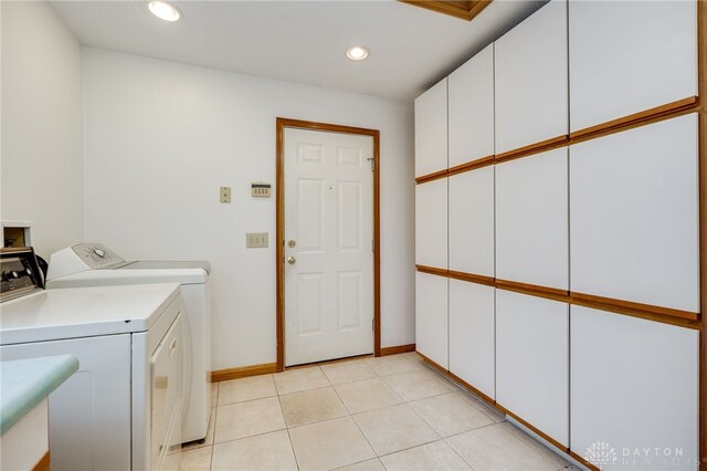 laundry area with cabinets, washing machine and dryer, and light tile patterned floors