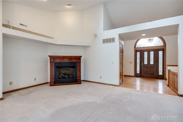 carpeted entrance foyer with high vaulted ceiling