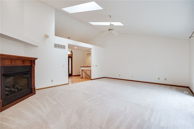 unfurnished living room featuring ceiling fan, high vaulted ceiling, a skylight, and light carpet