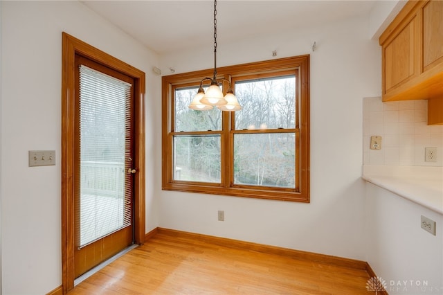 unfurnished dining area featuring a chandelier and light hardwood / wood-style flooring