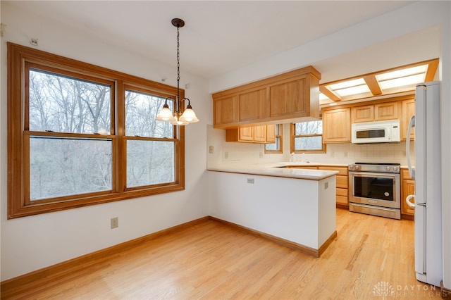 kitchen featuring kitchen peninsula, decorative light fixtures, tasteful backsplash, white appliances, and a notable chandelier