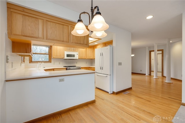 kitchen with white appliances, light brown cabinets, hanging light fixtures, kitchen peninsula, and a chandelier