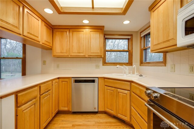 kitchen with sink, backsplash, light wood-type flooring, and appliances with stainless steel finishes