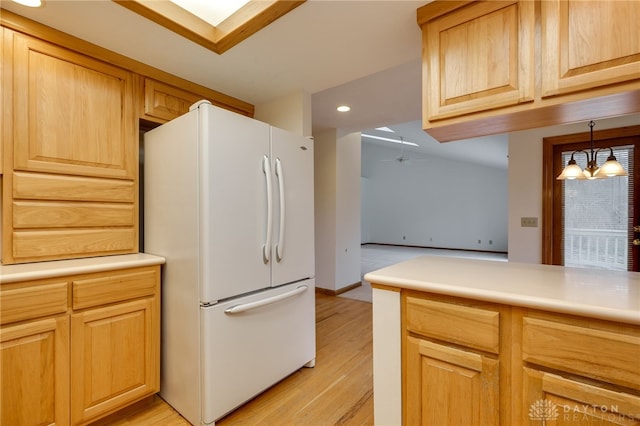 kitchen featuring pendant lighting, light brown cabinetry, white refrigerator, light wood-type flooring, and ceiling fan with notable chandelier