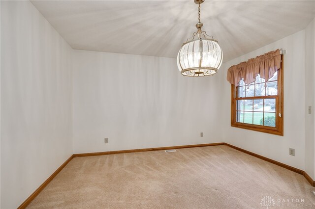 spare room with carpet and an inviting chandelier