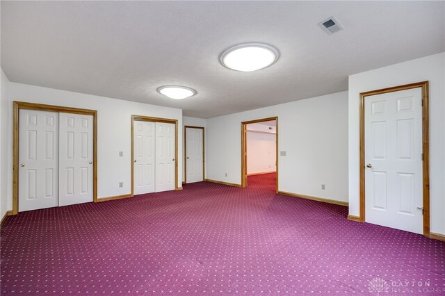 unfurnished bedroom with carpet floors and multiple closets