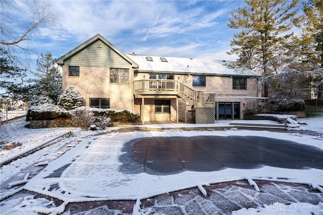 snow covered rear of property with a deck