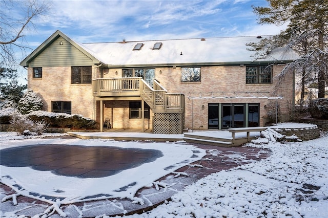 snow covered rear of property with a deck