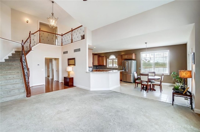 carpeted living room with a towering ceiling and a notable chandelier