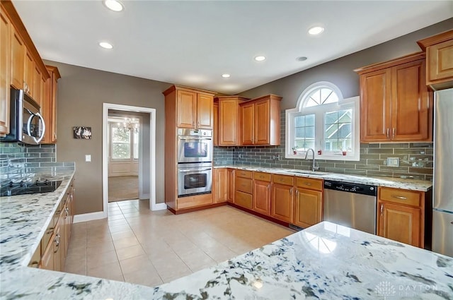 kitchen featuring backsplash, light stone counters, sink, and stainless steel appliances