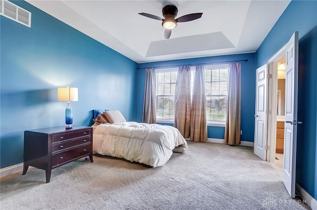 carpeted bedroom featuring a raised ceiling and ceiling fan