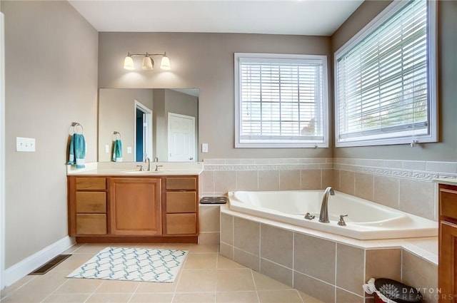 bathroom with tile patterned flooring, vanity, and tiled bath